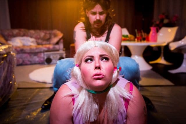 A man in the background choking a blonde lady